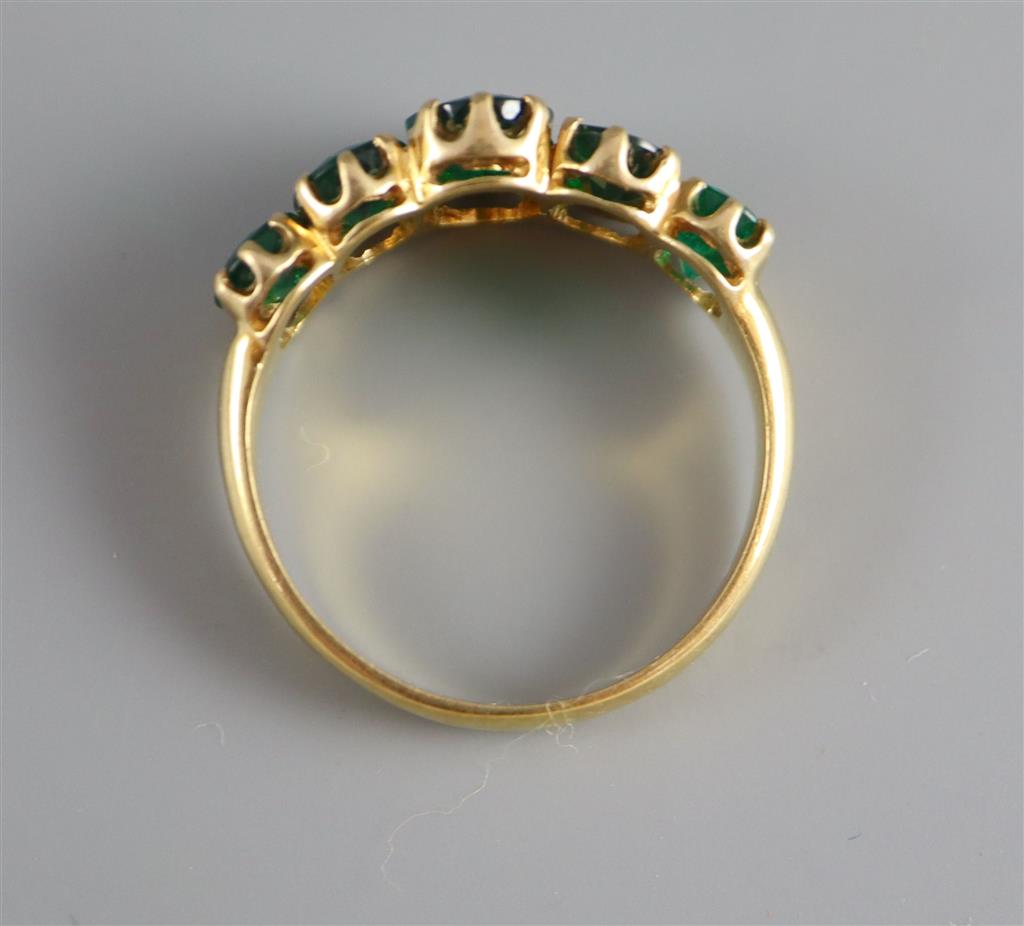 A mid to late 20th century gold and graduated five stone oval cut emerald set half hoop ring,